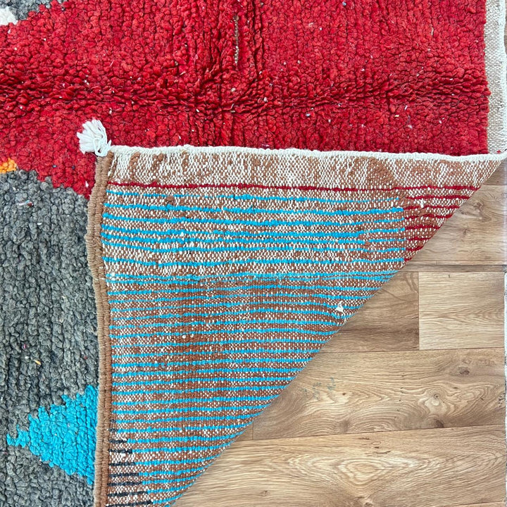 Vintage Moroccan wool rug with bold geometric Berber patterns in turquoise, red, and mustard
