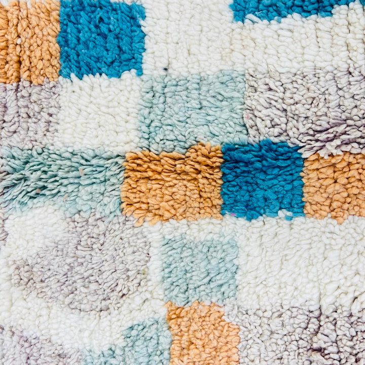 Vintage Moroccan wool rug with abstract Berber geometric pattern in beige, blue, and orange tones — handmade tribal carpet from Morocco.