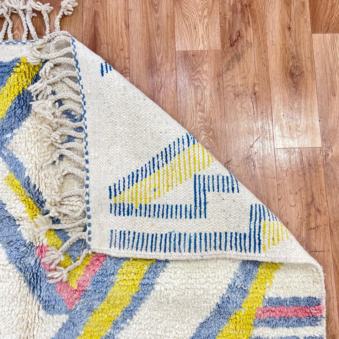 Vintage Moroccan wool rug with ivory base and diagonal geometric patterns in blue, yellow and pink