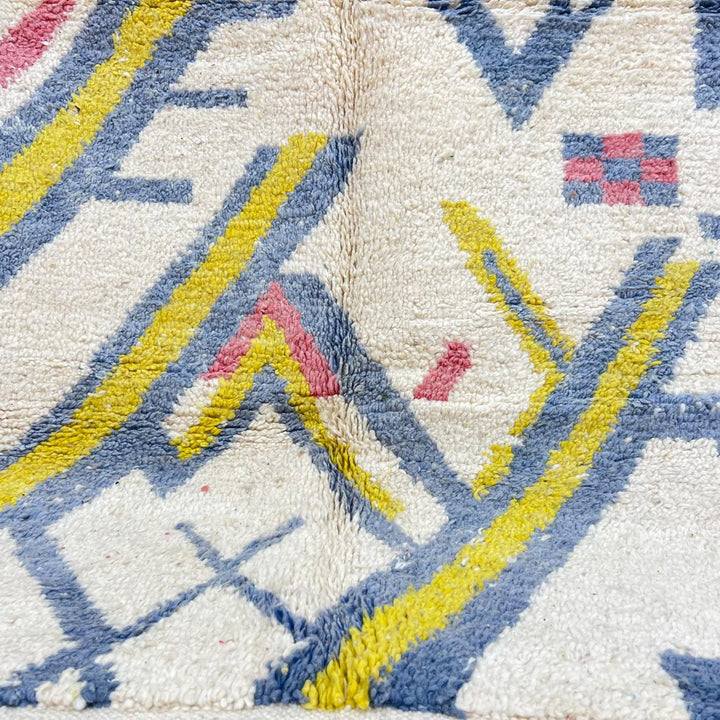 Vintage Moroccan wool rug with ivory base and diagonal geometric patterns in blue, yellow and pink
