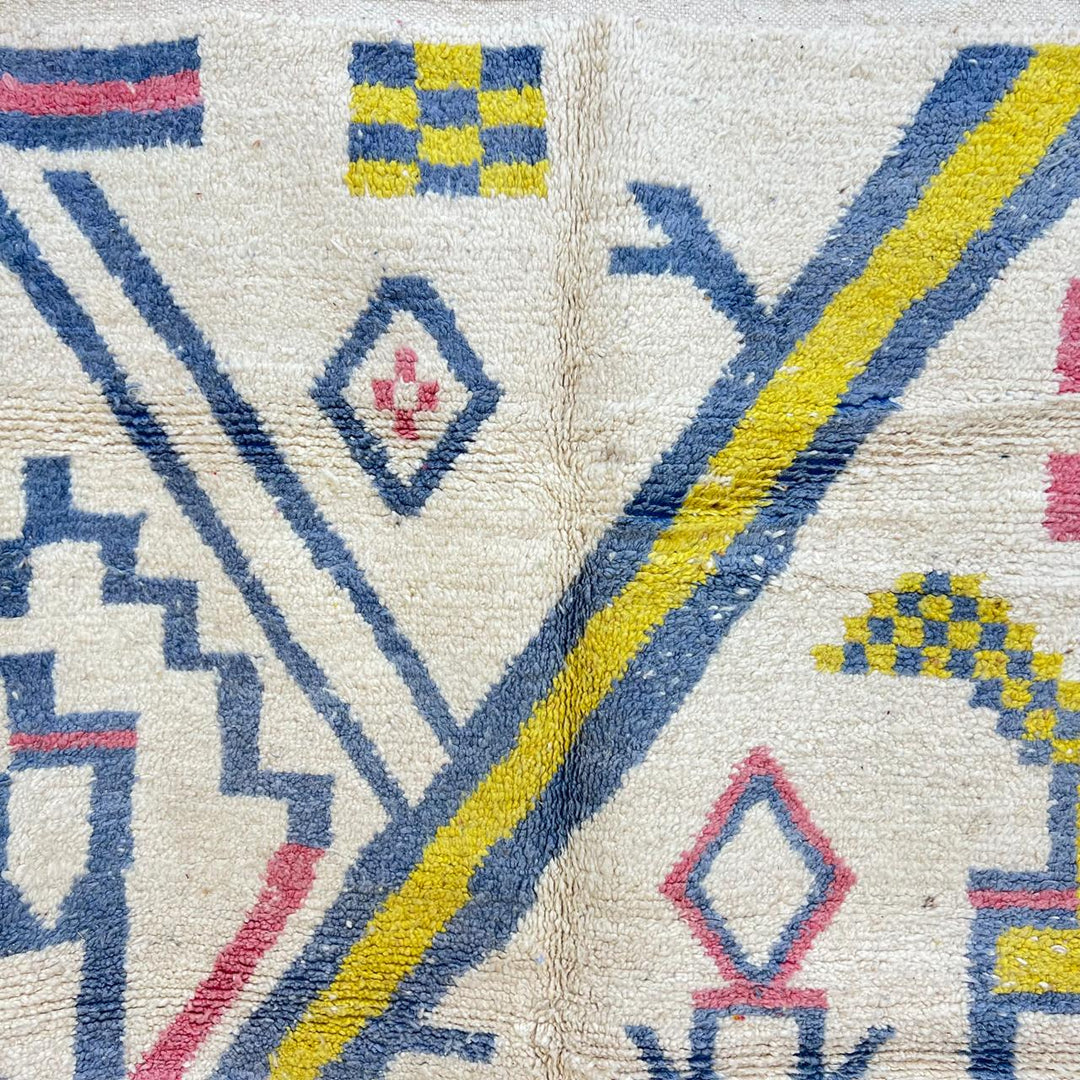 Vintage Moroccan wool rug with ivory base and diagonal geometric patterns in blue, yellow and pink