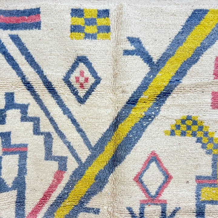 Vintage Moroccan wool rug with ivory base and diagonal geometric patterns in blue, yellow and pink