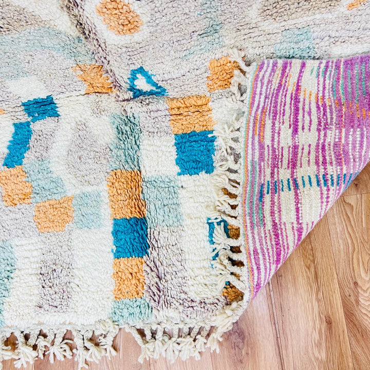 Vintage Moroccan wool rug with abstract Berber geometric pattern in beige, blue, and orange tones — handmade tribal carpet from Morocco.