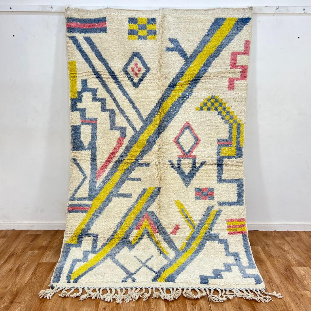 Vintage Moroccan wool rug with ivory base and diagonal geometric patterns in blue, yellow and pink