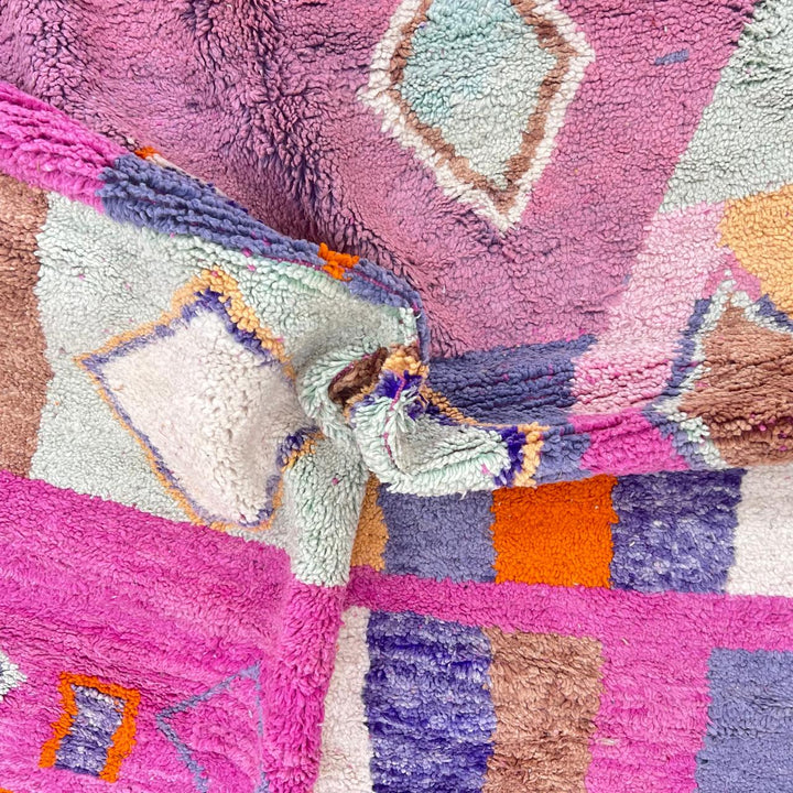 Vintage Moroccan wool rug with pink base and colorful Berber geometric diamond patterns, handmade in Morocco.