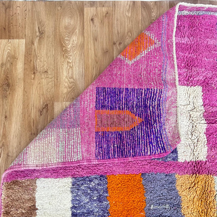 Vintage Moroccan wool rug with pink base and colorful Berber geometric diamond patterns, handmade in Morocco.