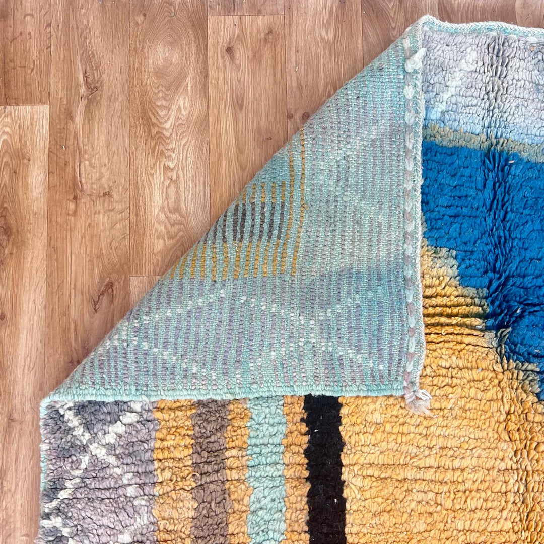 Vintage Moroccan wool rug with yellow base and blue, black Berber geometric patterns, handmade in Morocco.