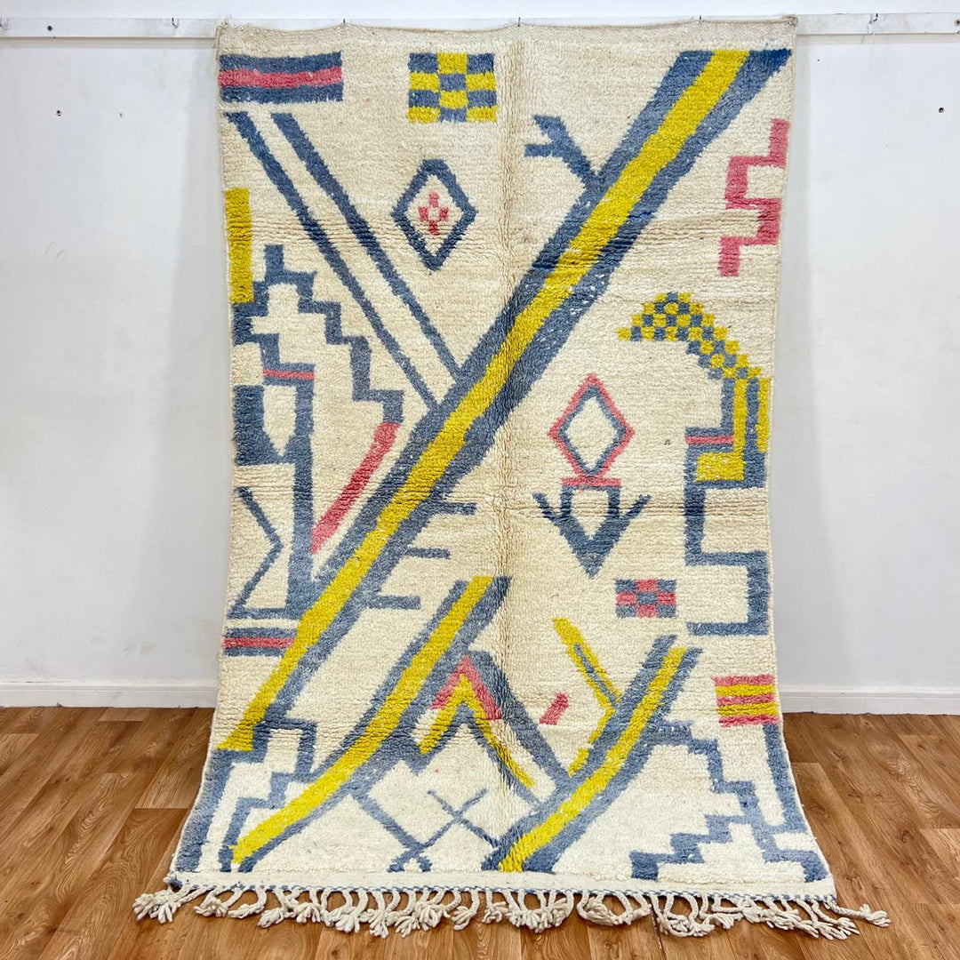 Vintage Moroccan wool rug with ivory base and diagonal geometric patterns in blue, yellow and pink
