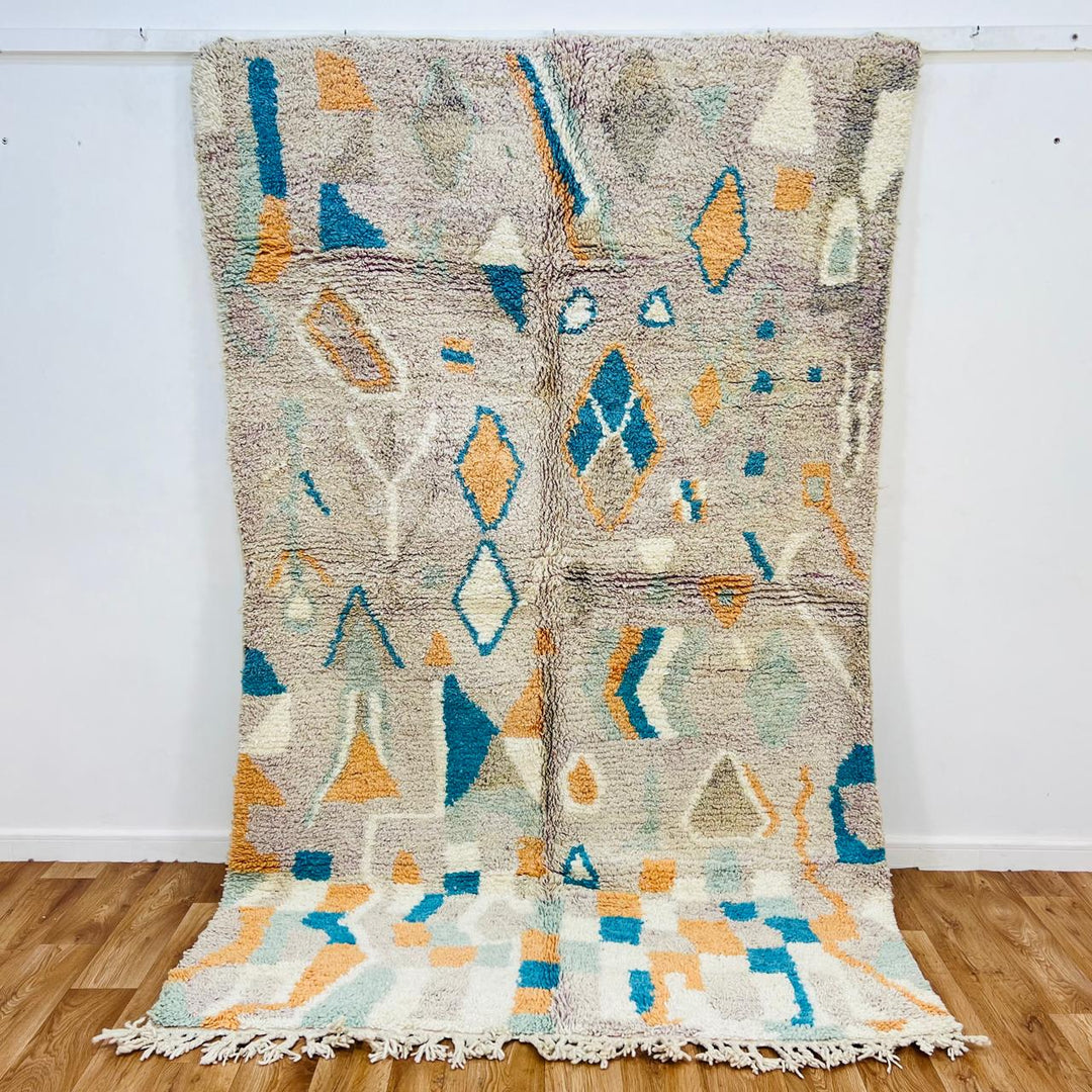 Vintage Moroccan wool rug with abstract Berber geometric pattern in beige, blue, and orange tones — handmade tribal carpet from Morocco.