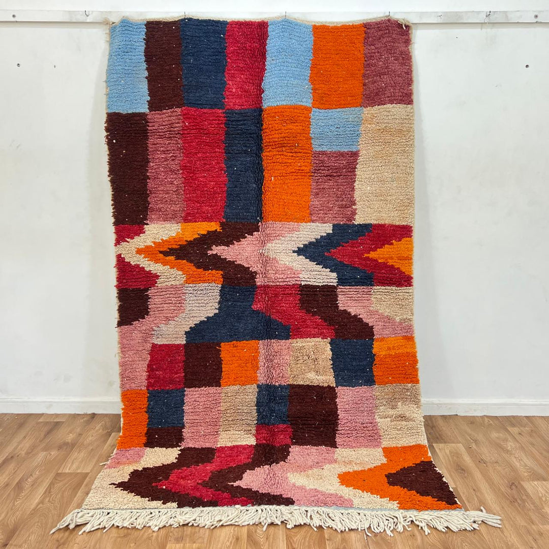 Vintage Moroccan wool rug with colorful geometric Berber design in orange, pink, blue and beige tones.