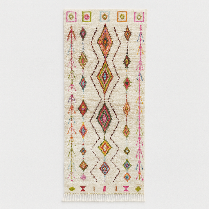 Handmade white Moroccan runner rug with colorful Berber diamond motifs and tribal patterns, crafted from natural wool for hallways and modern interiors.