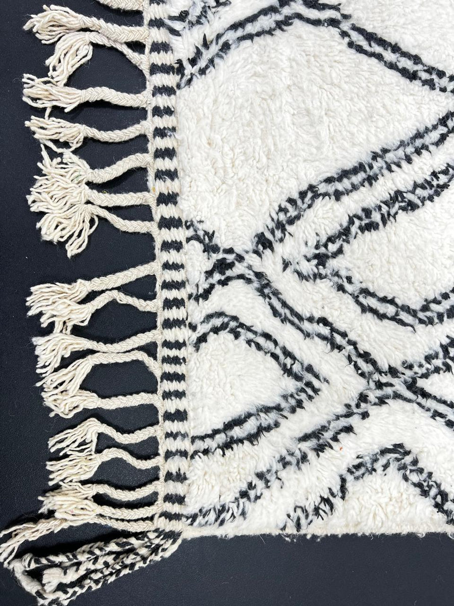 Handmade white Moroccan runner rug with black diamond lattice pattern in natural wool, Berber inspired design.