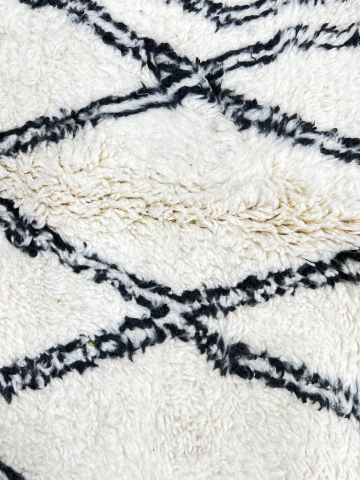 Handmade white Moroccan runner rug with black diamond lattice pattern in natural wool, Berber inspired design.