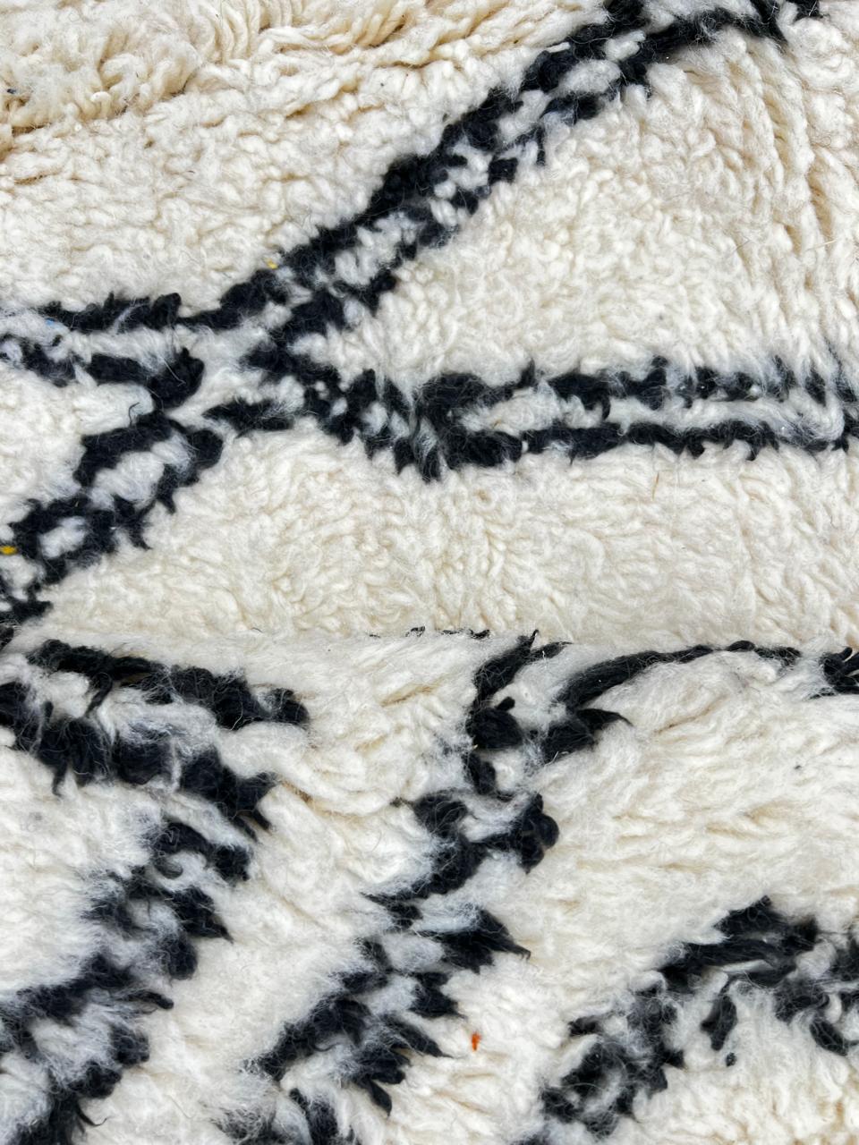 Handmade white Moroccan runner rug with black diamond lattice pattern in natural wool, Berber inspired design.
