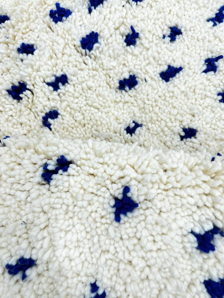 Handmade white Moroccan runner rug with small blue dotted pattern, woven from natural wool by Berber artisans.