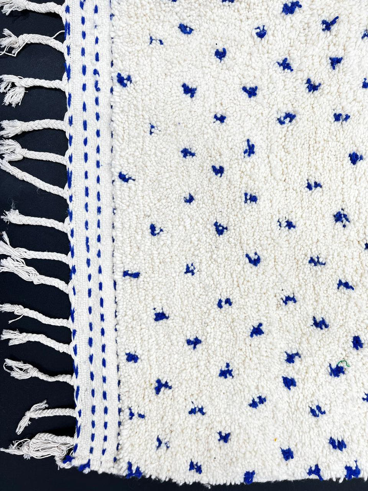 Handmade white Moroccan runner rug with small blue dotted pattern, woven from natural wool by Berber artisans.