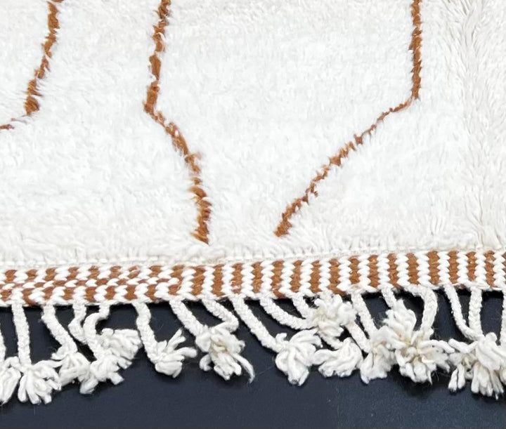 Handmade white Moroccan runner rug with brown abstract elongated motifs, crafted from natural wool by Berber artisans.