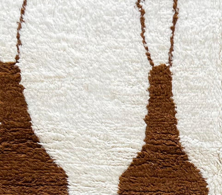 Handmade white Moroccan runner rug with brown abstract elongated motifs, crafted from natural wool by Berber artisans.