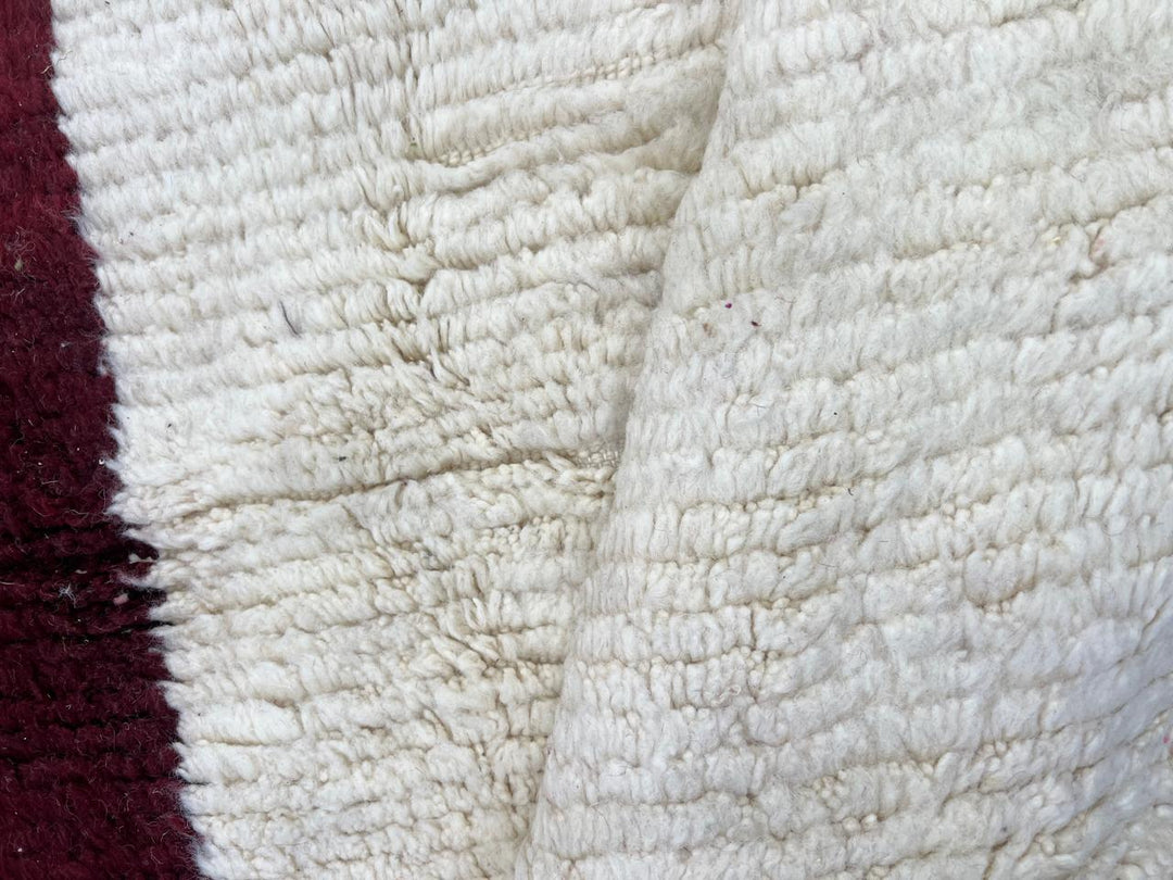 White Moroccan runner rug with a deep red vertical stripe and purple horizontal stripe, handmade from natural wool