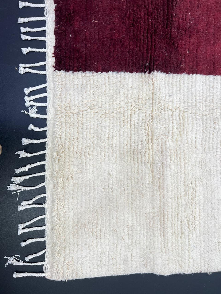 White Moroccan runner rug with a deep red vertical stripe and purple horizontal stripe, handmade from natural wool