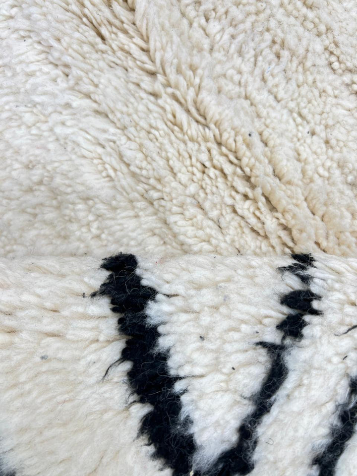 Round white Moroccan wool rug with black Berber diamond motifs in a minimalist design.