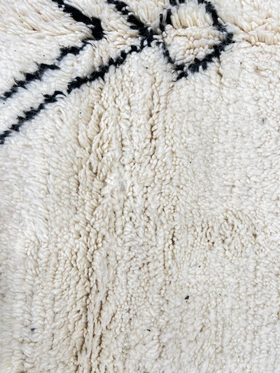 Round white Moroccan wool rug with black Berber diamond motifs in a minimalist design.