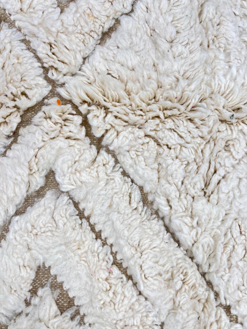 Round white Moroccan wool rug with carved geometric diamond and chevron patterns.