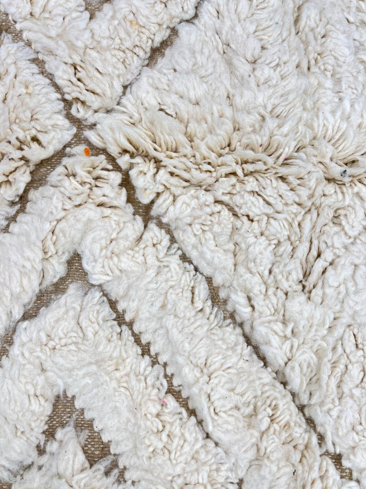 Round white Moroccan wool rug with carved geometric diamond and chevron patterns.