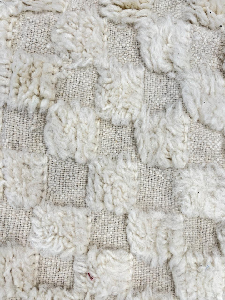 Round white Moroccan wool rug with raised checkered 3D texture.