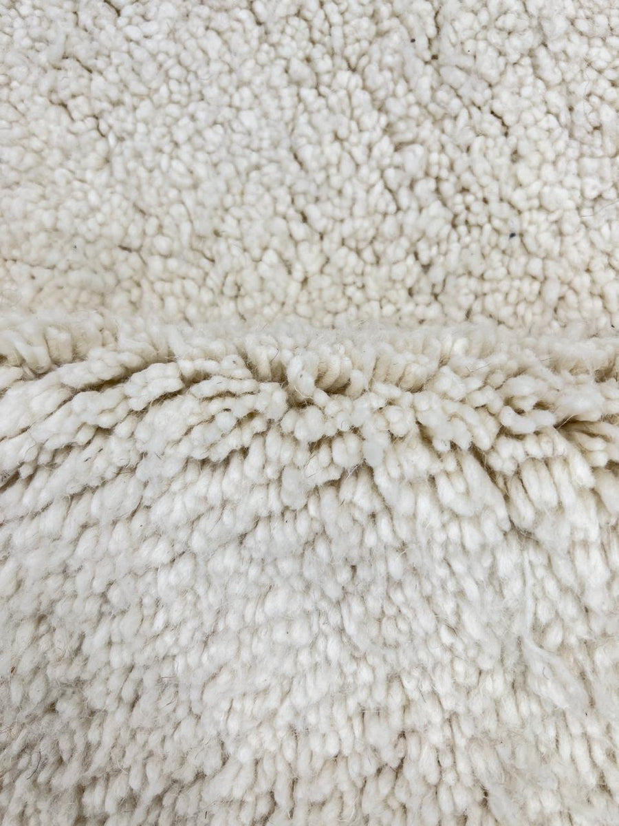 Round white Moroccan wool rug with soft plush texture and minimalist design.