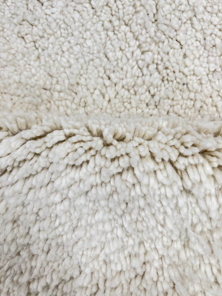 Round white Moroccan wool rug with soft plush texture and minimalist design.