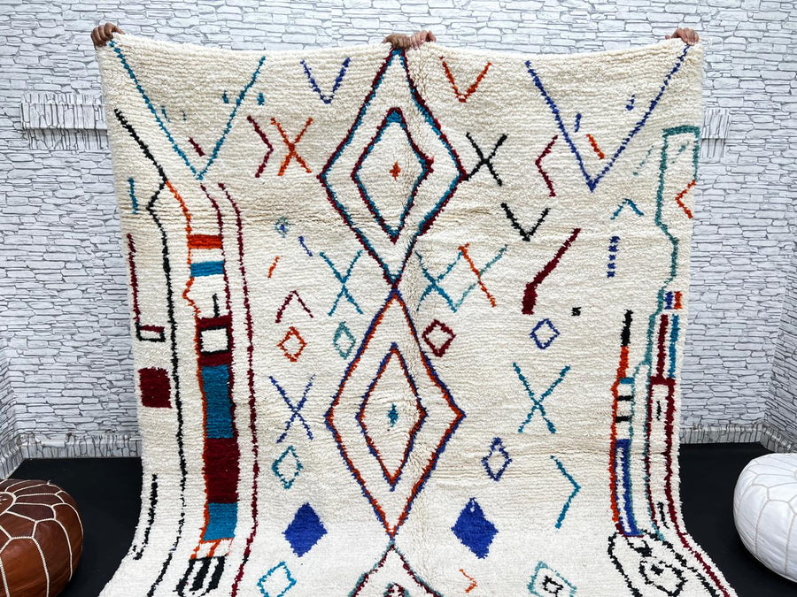 Handmade white Moroccan wool rug with blue, red, and orange geometric motifs – Berber design