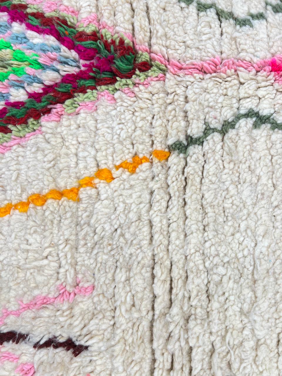 Handmade white Moroccan wool runner rug with colorful Berber diamond motifs in pink, green, yellow, turquoise, and black