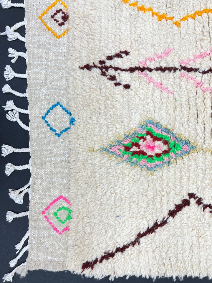 Handmade white Moroccan wool runner rug with colorful Berber diamond motifs in pink, green, yellow, turquoise, and black