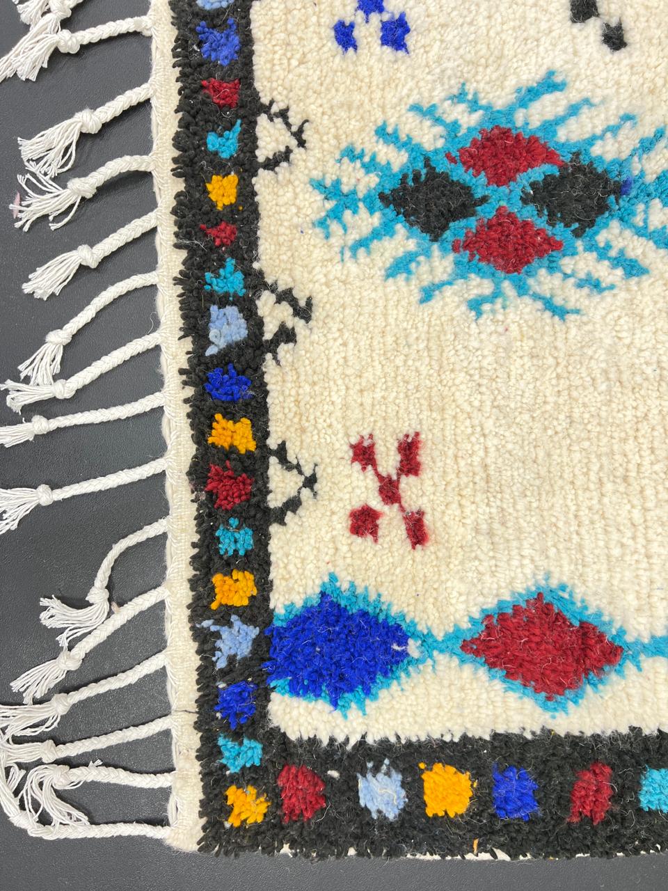 Handmade white Moroccan wool runner rug with colorful tribal Berber motifs in blue, red, yellow, turquoise, and orange