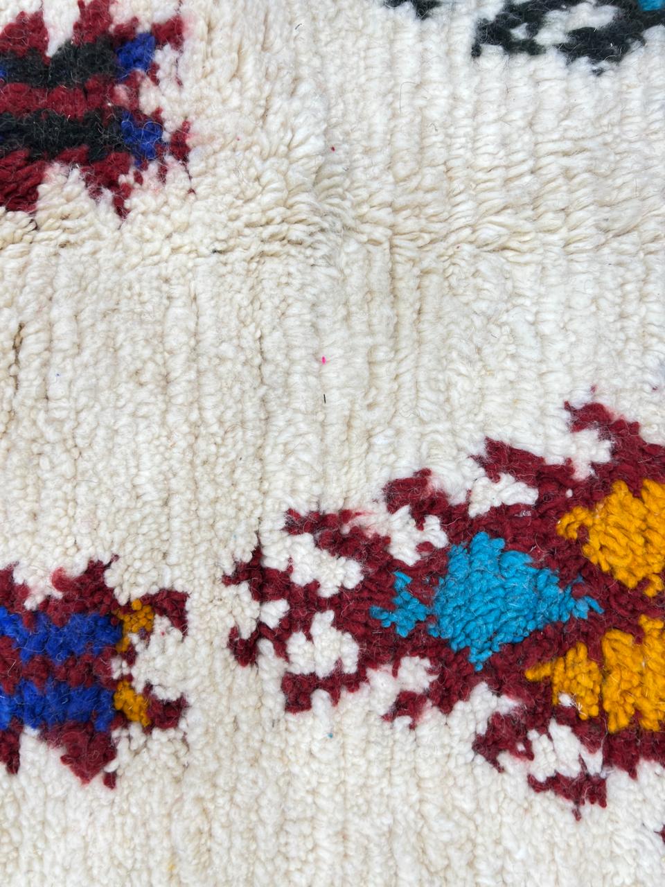 Handmade white Moroccan wool runner rug with colorful tribal Berber motifs in blue, red, yellow, turquoise, and orange