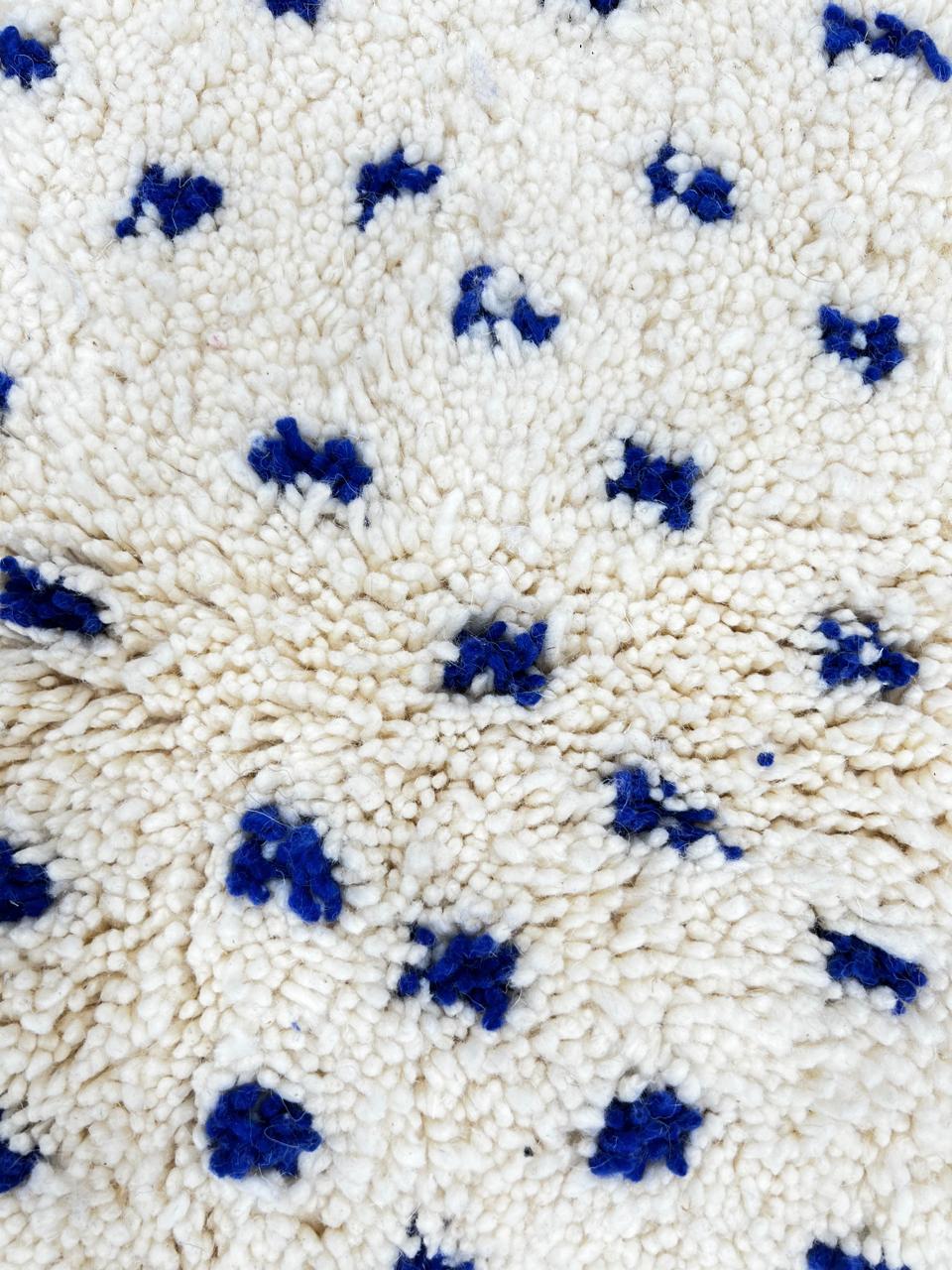Round white Moroccan rug with small blue dotted pattern, handmade wool design