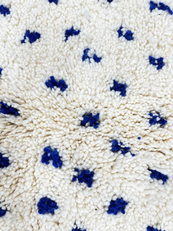 Round white Moroccan rug with small blue dotted pattern, handmade wool design