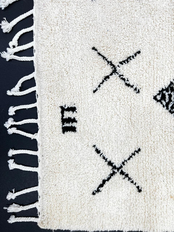 Handmade white Moroccan runner rug with black tribal Berber symbols and diamond patterns.
