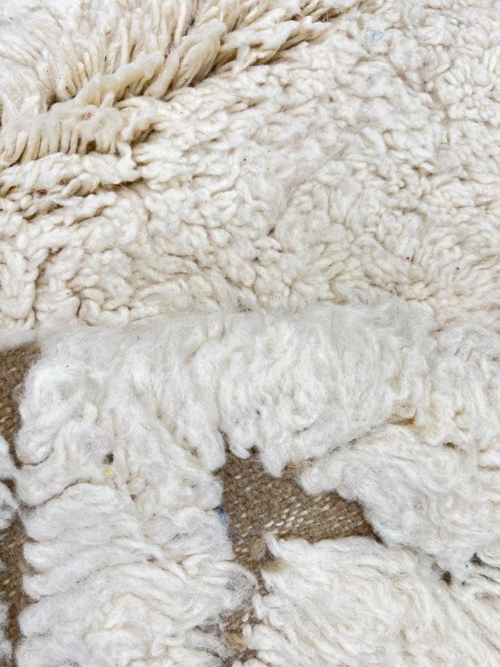 Round white Moroccan wool rug with carved geometric diamond and chevron patterns.