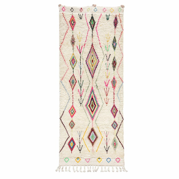 Handmade white Moroccan wool runner rug with colorful Berber diamond motifs in pink, green, yellow, turquoise, and black