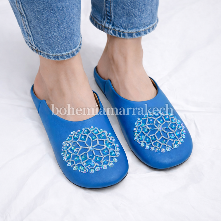Traditional Moroccan leather babouche slippers in blue, featuring artisan beaded medallion design.