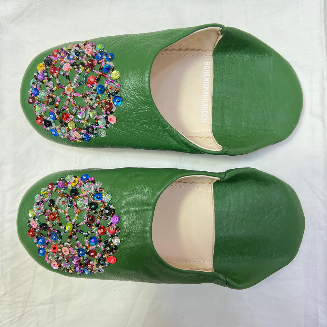 Green handmade Moroccan leather babouche slippers with colorful beaded medallion.