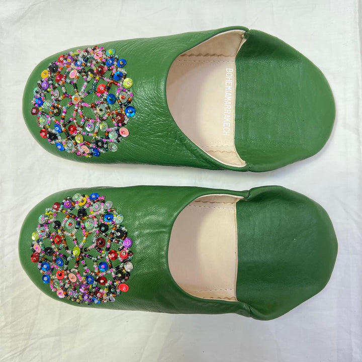 Green handmade Moroccan leather babouche slippers with colorful beaded medallion.