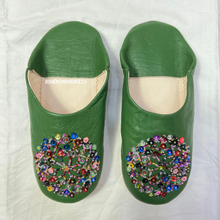 Green handmade Moroccan leather babouche slippers with colorful beaded medallion.
