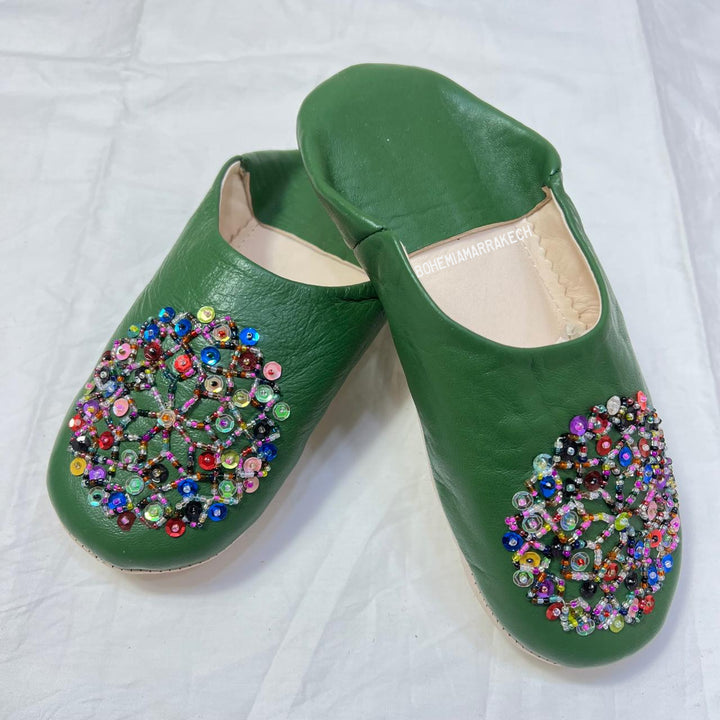 Green handmade Moroccan leather babouche slippers with colorful beaded medallion.