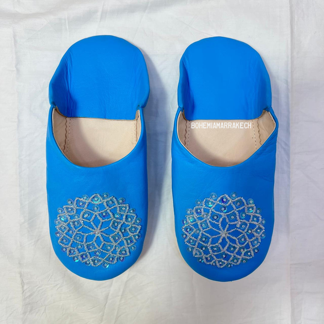 Traditional Moroccan leather babouche slippers in blue, featuring artisan beaded medallion design.