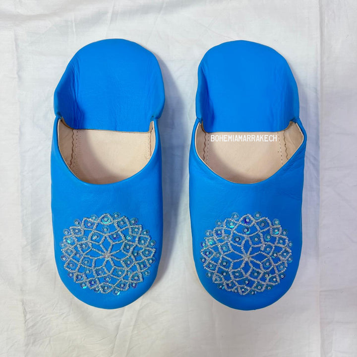 Traditional Moroccan leather babouche slippers in blue, featuring artisan beaded medallion design.