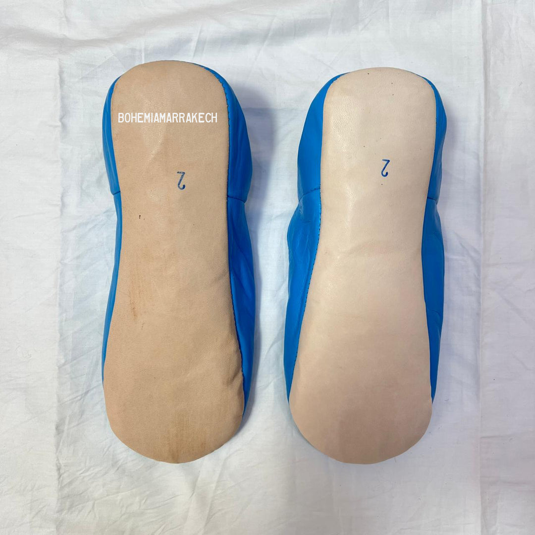 Traditional Moroccan leather babouche slippers in blue, featuring artisan beaded medallion design.