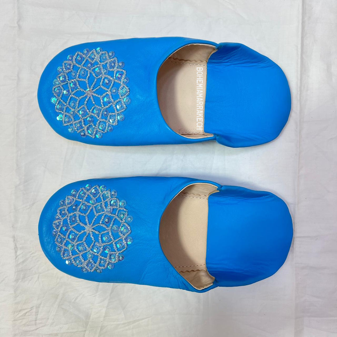 Traditional Moroccan leather babouche slippers in blue, featuring artisan beaded medallion design.